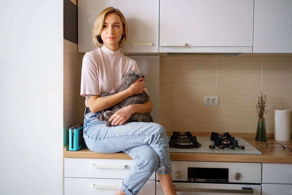 usmiechnieta-kobieta-bawic-sie-z-kotem-w-kuchni-w-domu_Easy-Resize.com