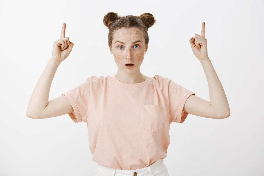 zdziwiona-i-zdumiona-ruda-dziewczyna-wskazujac-palcami-w-gore_Easy-Resize.com